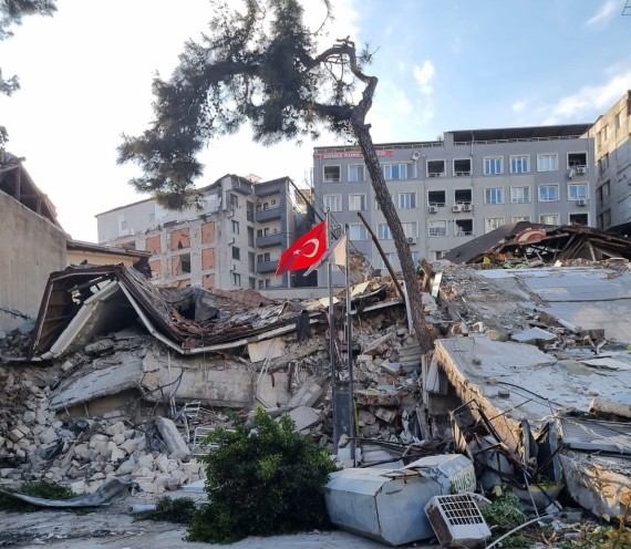 Türkische Flagge vor zusammen gestürtzem Gebäude. 